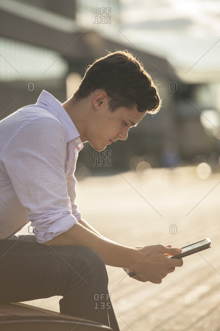Male student in outdoor urban area studying on tablet