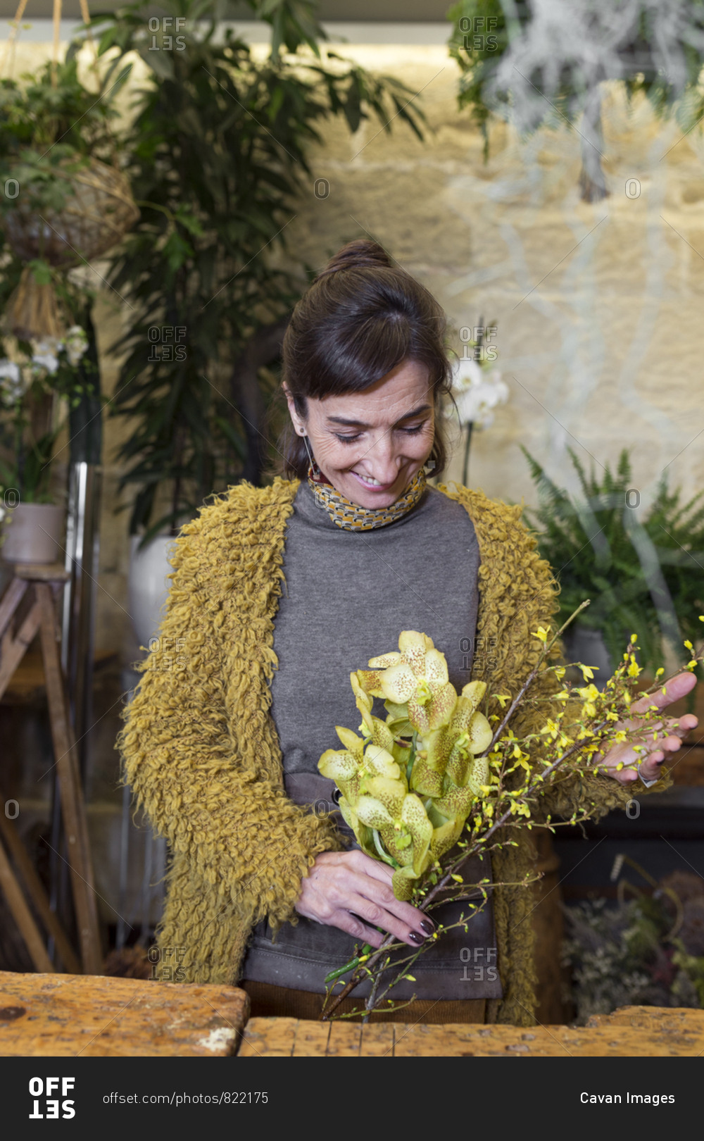 Portrait of cheerful woman holding yellow flowers at slower shop