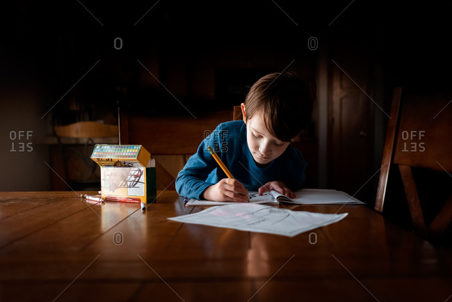 A young small boy doing homework at a table