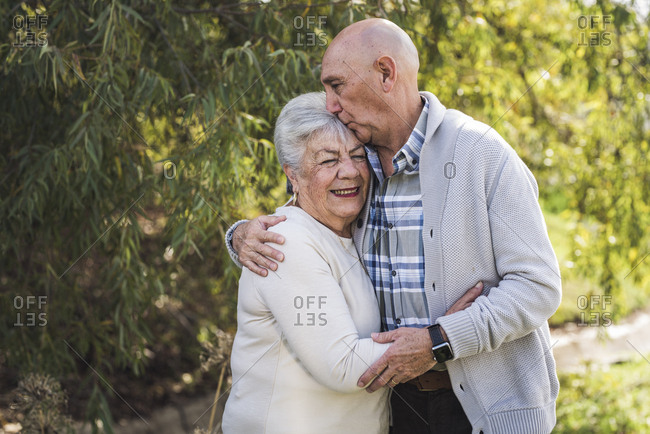 Portrait of grandfather kissing his mothers forehead outside