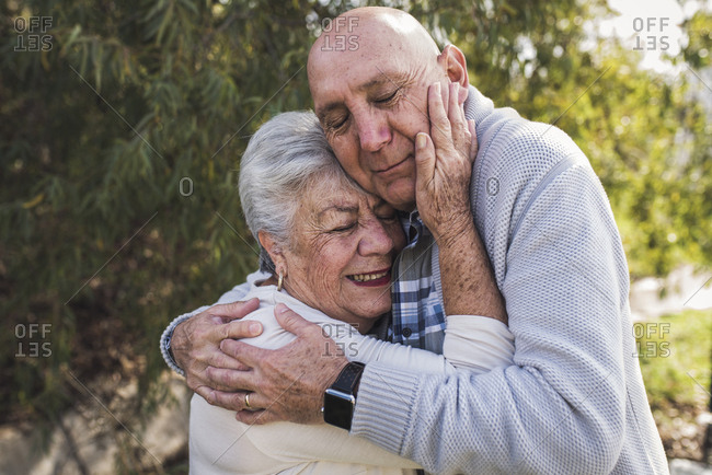 Close up portrait of grandfather and his mother embracing outside