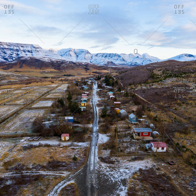 Road between buildings, fields and hills in snow