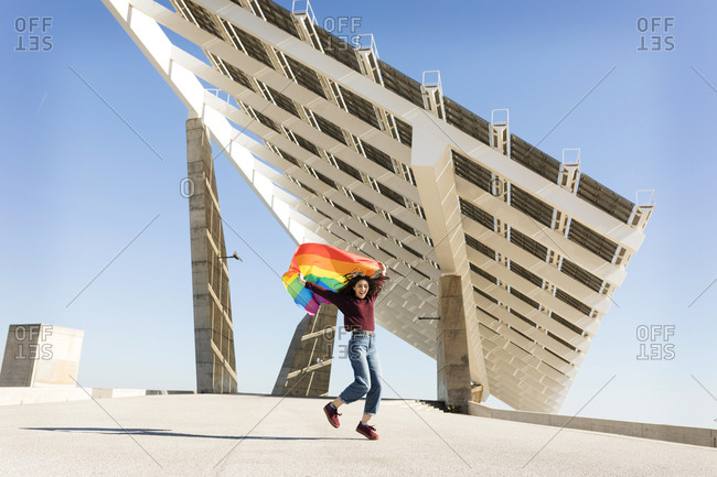 Brunette girl with gay pride flag on a windy day