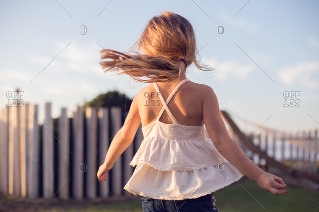 Little girl imagining she's a dancer, spinning and twirling in the sun