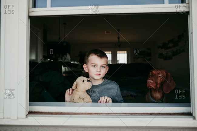 A boy and dog looking out of a window