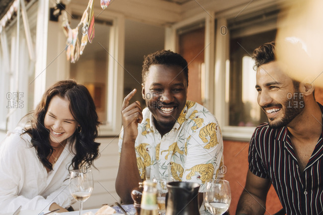 Cheerful friends having fun at dining table during dinner party
