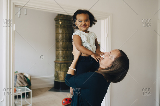 Happy mother holding daughter while standing at home