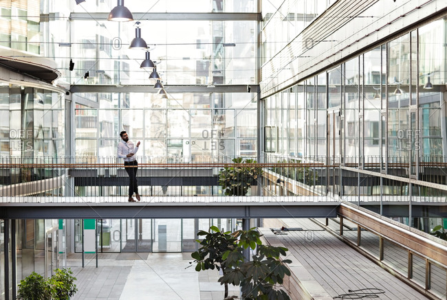 Full length of young businessman standing at atrium in office stock photo -  OFFSET