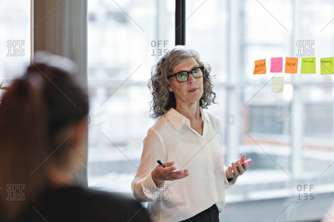 Senior confident businesswoman giving presentation in board room at office