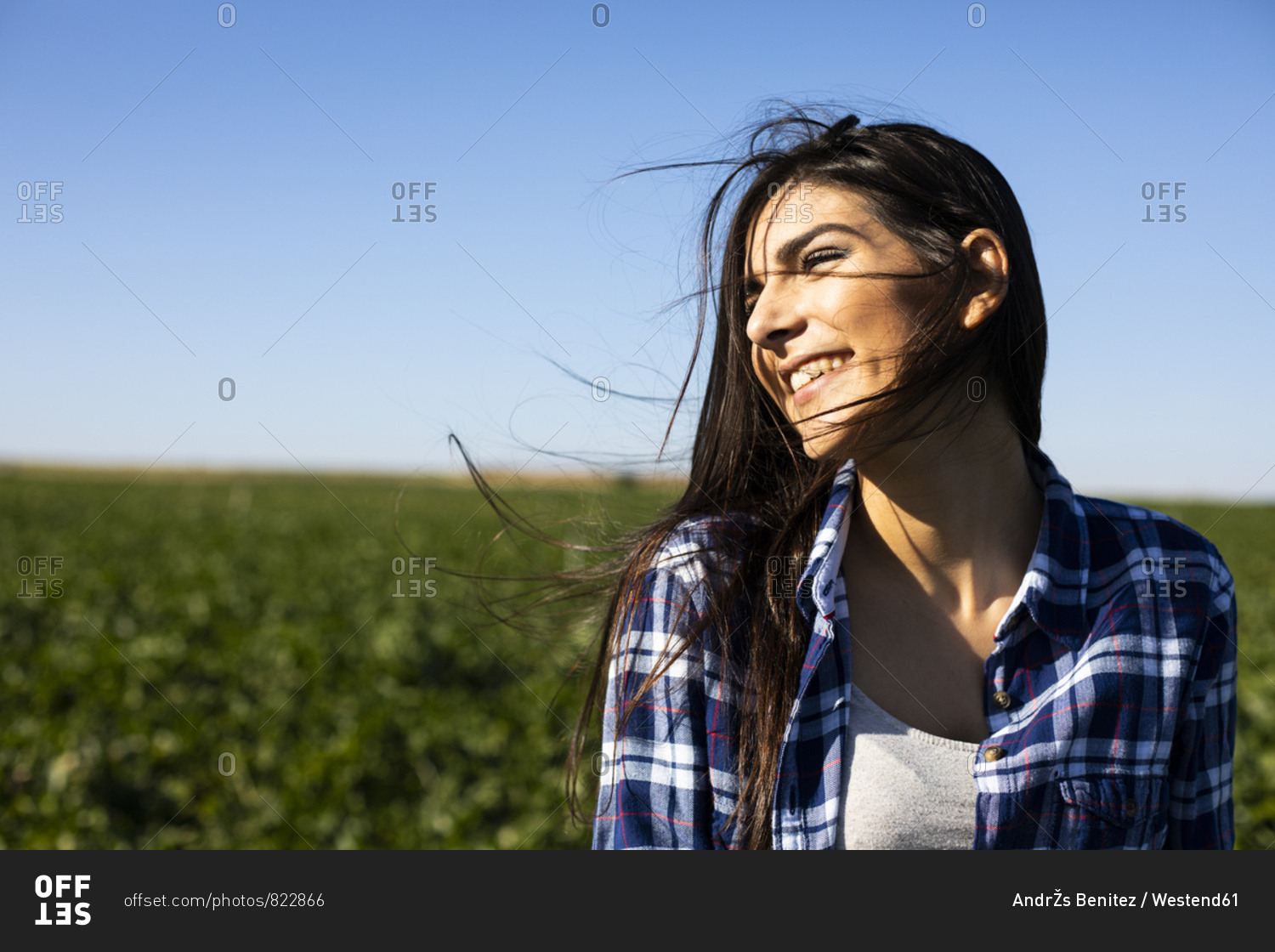 Young woman farmer with hoe on field
