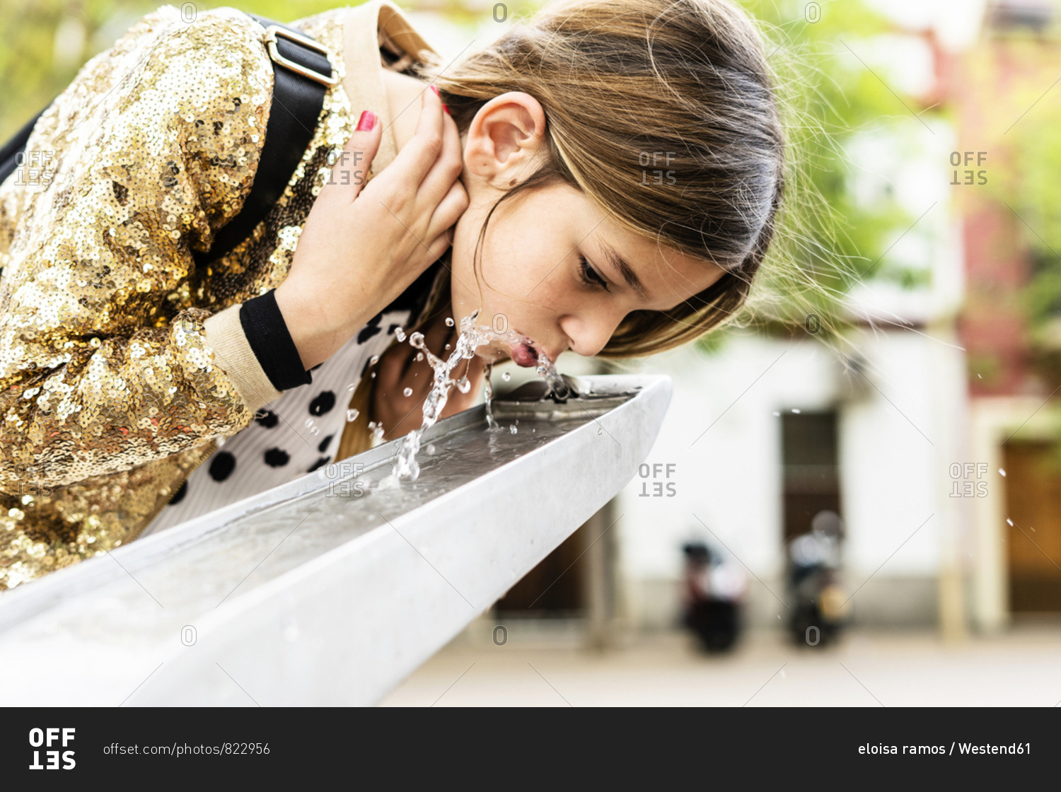 Girl drinking water of a fountain