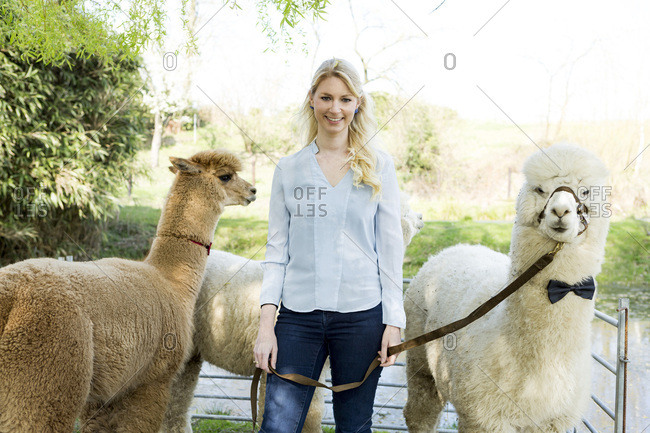 Portrait of happy woman with her alpacas