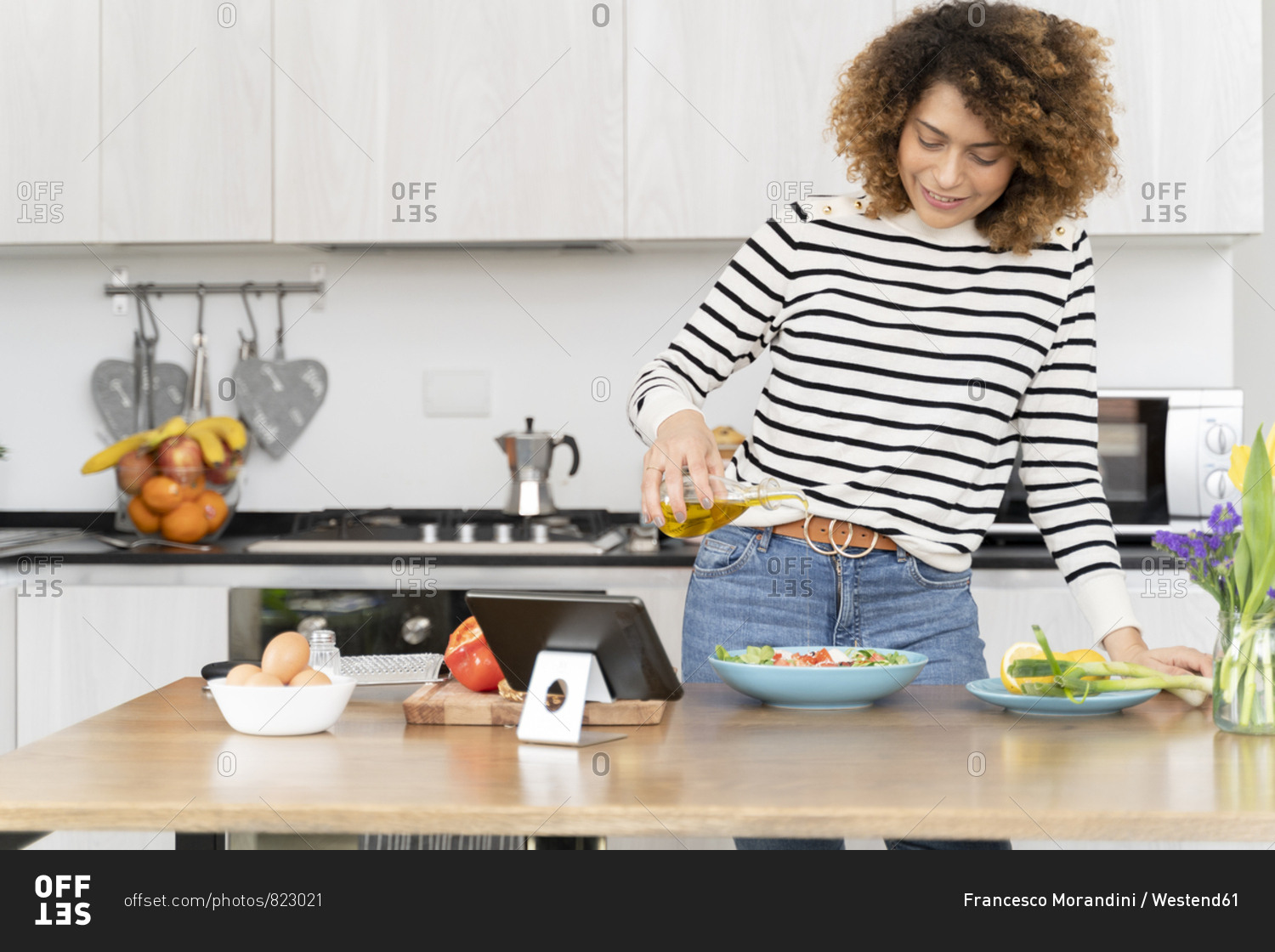 Woman standing in kitchen- preparing salad for lunch