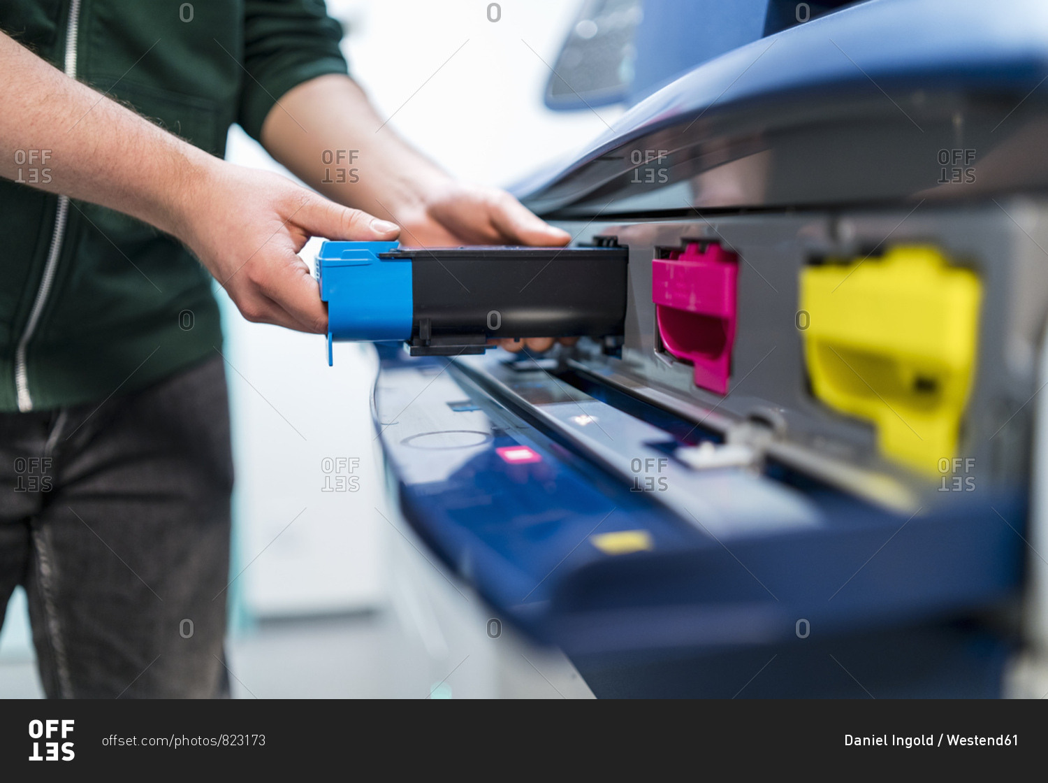 Close-up of teenager working at color printer inserting print cartridge