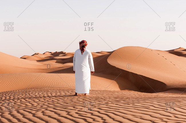 Bedouin in National dress standing in the desert- rear view- Wahiba Sands- Oman