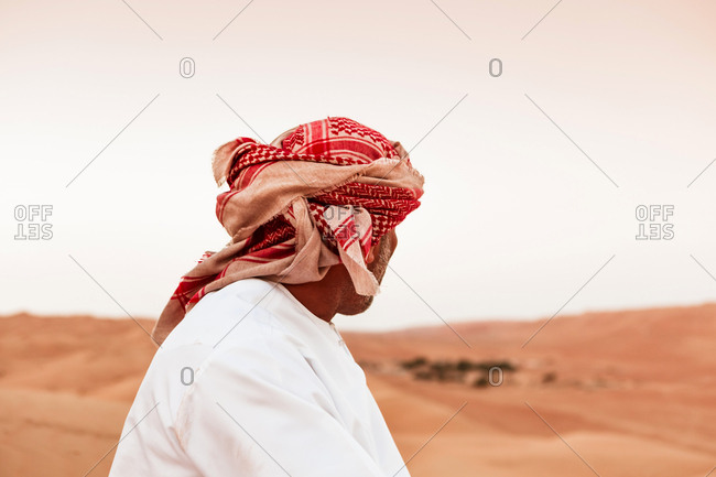 Bedouin in National dress standing in the desert- rear view- Wahiba Sands- Oman
