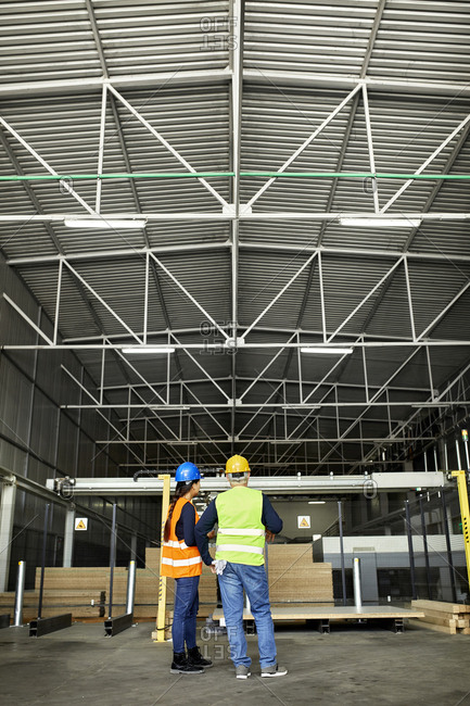 Rear view of male and female worker standing in factory workshop