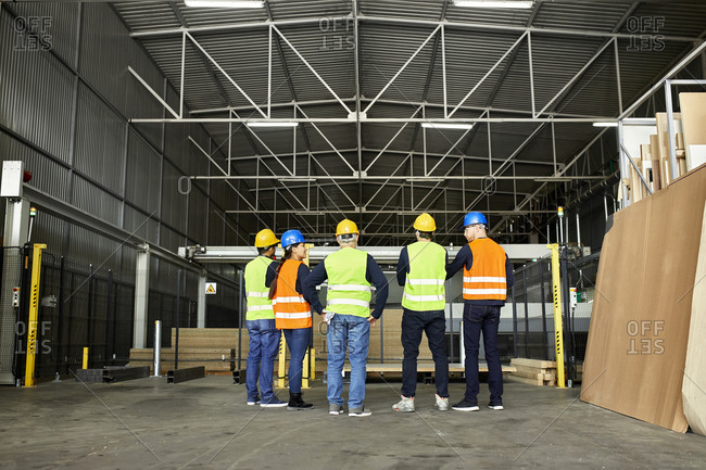 Rear view of workers standing in factory workshop