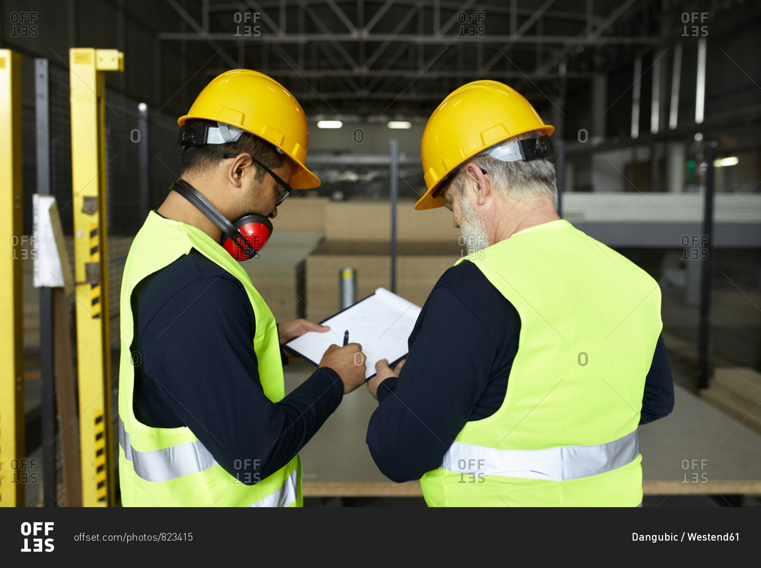 Two men signing document in factory warehouse