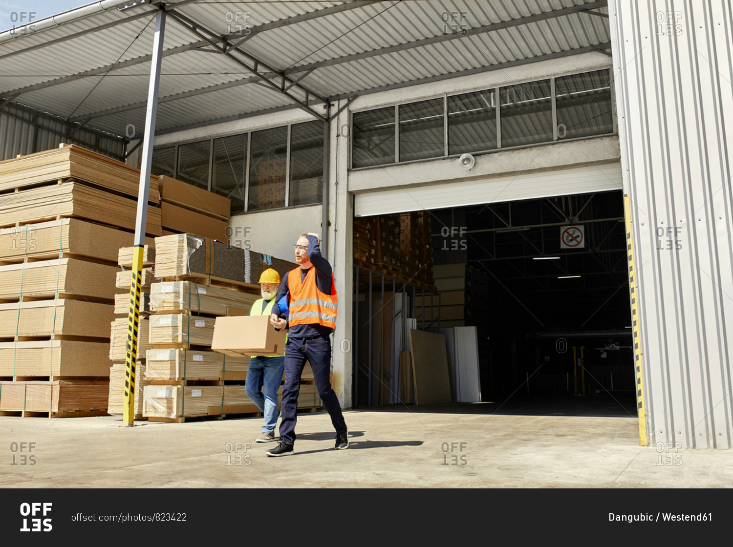 Two workers with box walking on factory yard