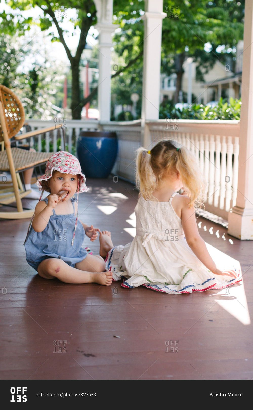 Two little girls sitting on porch eating fudge bars