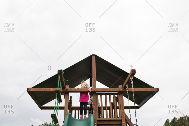 Cute Blonde Preschool Girl Plays on Top of Playground Set