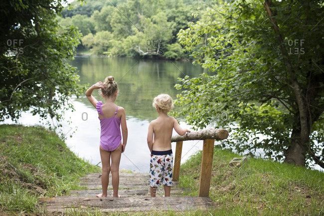 Rear View of Blonde Siblings Standing on Stairs Walking Down to Lake