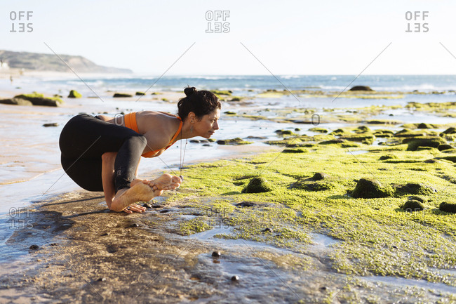 Mature woman practicing yoga on beach, on a very windy and sunny day.