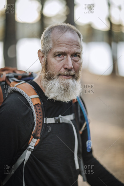 A portrait of a grey bearded retiree hiker with a backpack in Maine