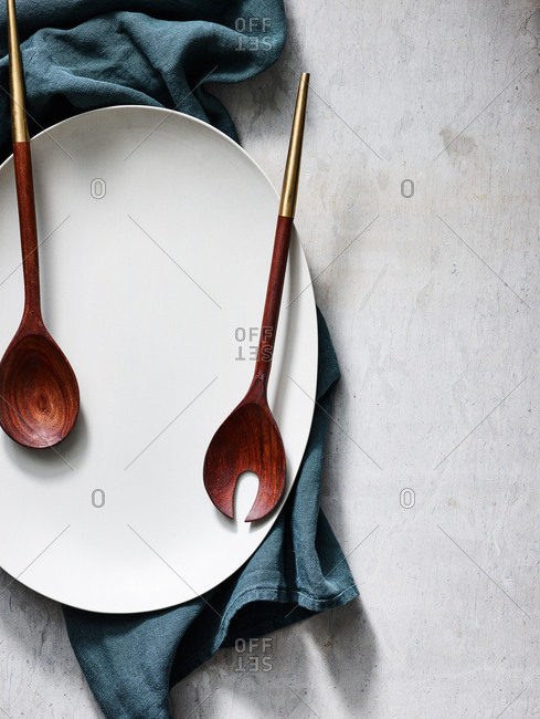 Overhead view of large plate with utensils and towel on light background