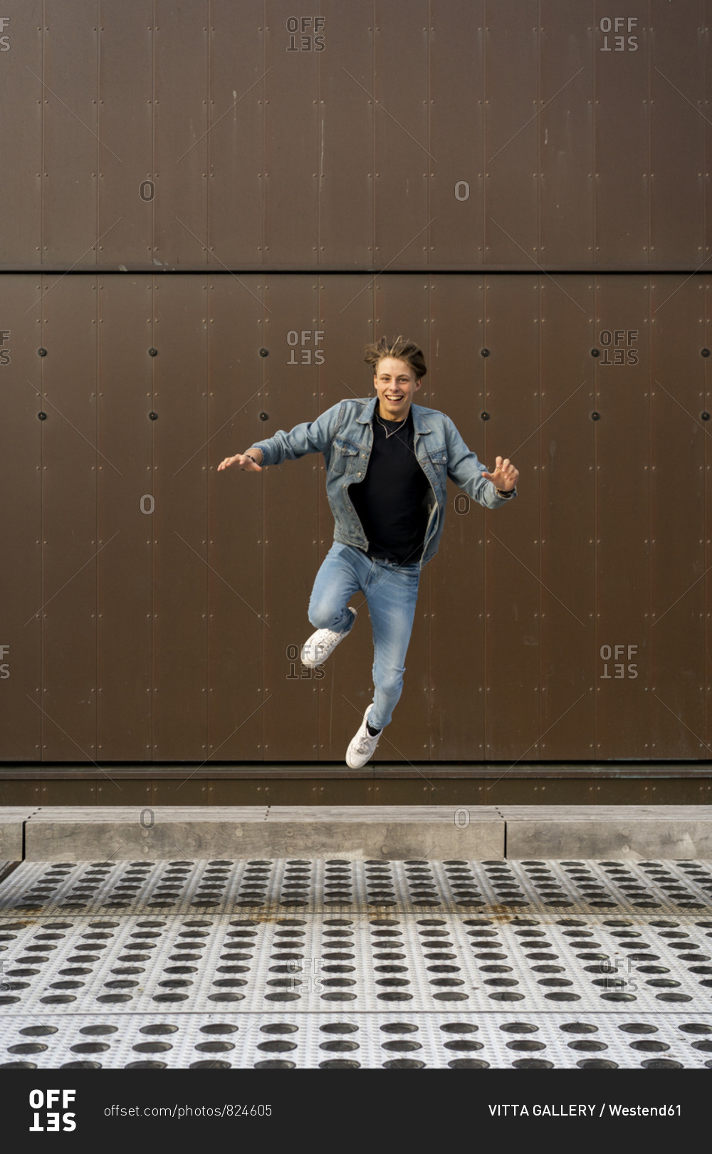Young man jumping in front of a wall