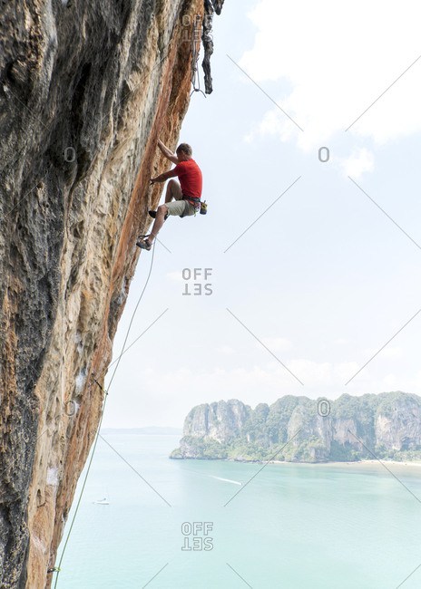 Thailand- Krabi- Thaiwand wall- man climbing in rock wall above the sea