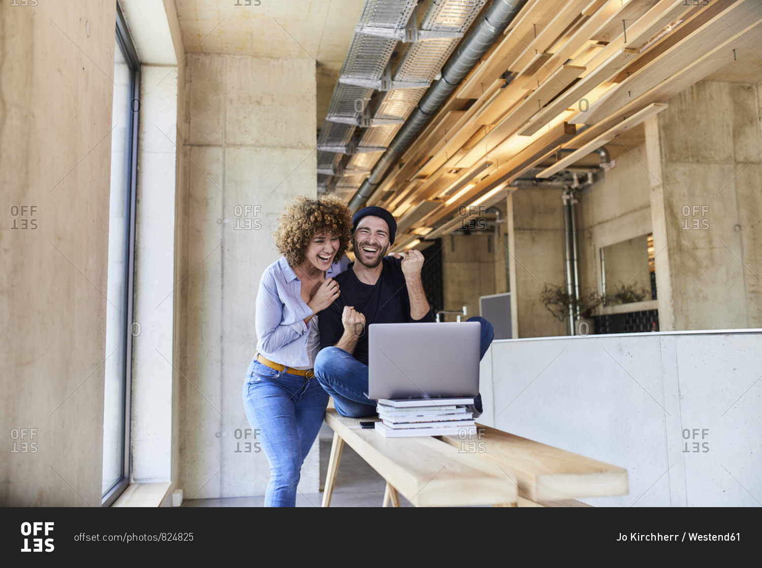 Excited man and woman with laptop in modern office