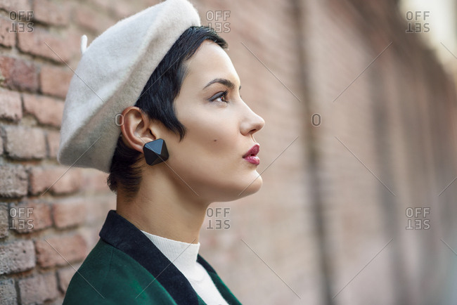 Fashionable young woman wearing a beret at a brick wall