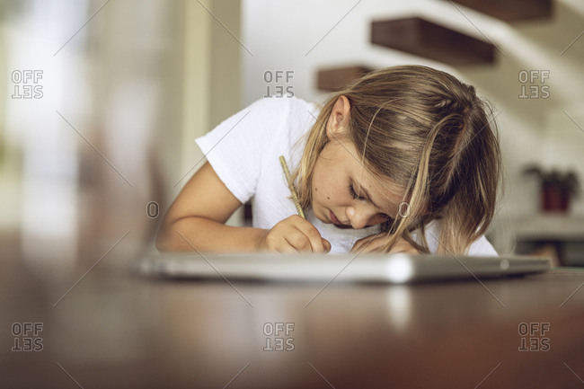 Girl sitting at table writing into diary