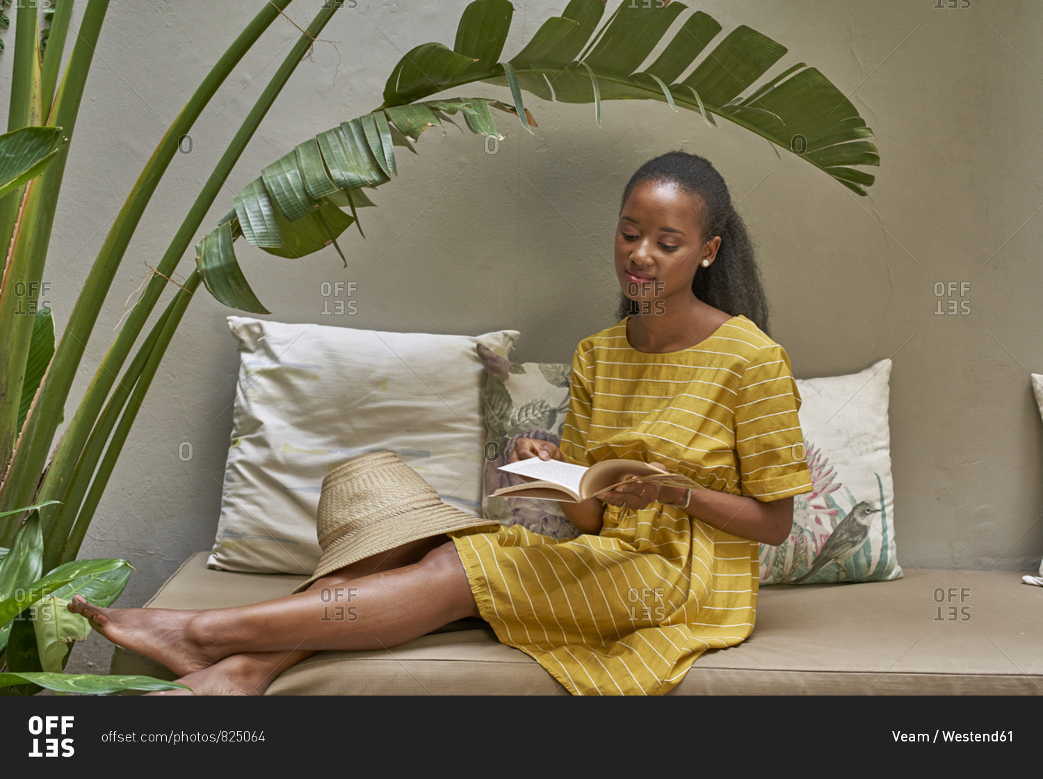 Relaxed young woman sitting on a couch reading a book