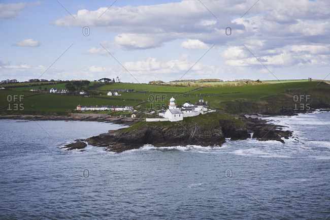 Roches Point, Cork, Ireland - May 09, 2019: A view of Roches Point and Roches Point lighthouse with clouds, sea and green fields.