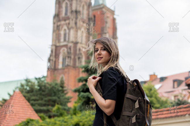 young girl with a backpack on the background of the old church in Europe