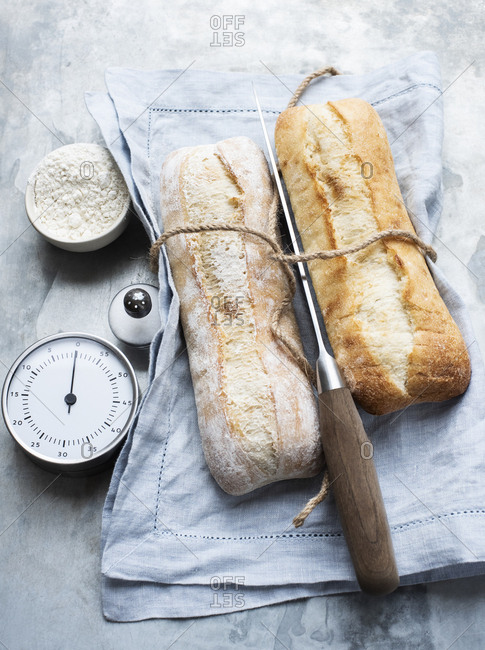 Two small baguettes on linen towels with a knife