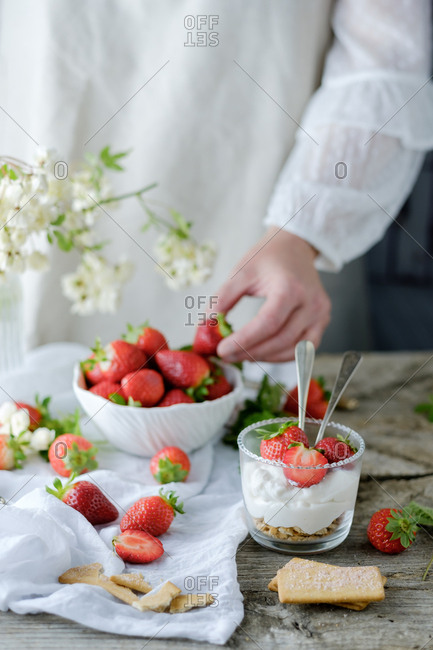 Faceless chef using fresh juicy tasty strawberries while preparing creamy sweet dessert