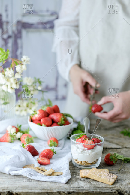 Faceless chef using fresh juicy tasty strawberries while preparing creamy sweet dessert
