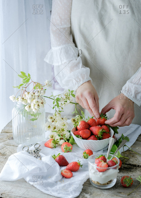 Faceless chef using fresh juicy tasty strawberries while preparing creamy sweet dessert