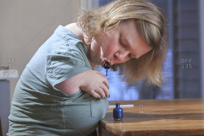 Woman with TAR Syndrome painting her nails at home.
