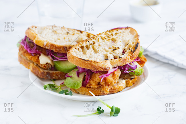 Lunch sandwich with avocado, fried chicken and sliced red cabbage served with mustard sauce