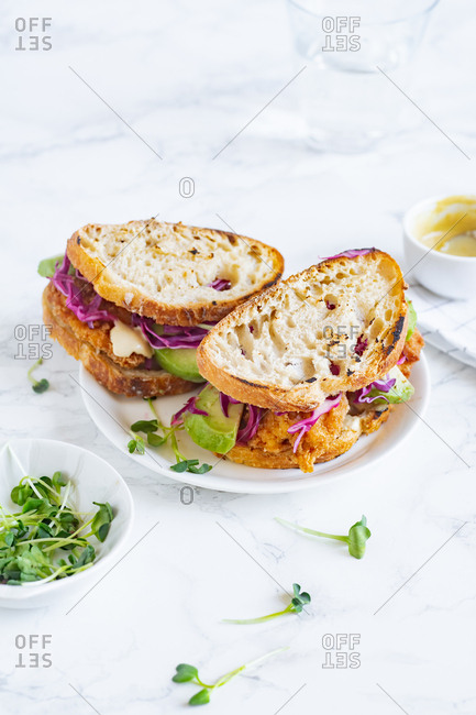 Lunch sandwich with avocado, fried chicken and sliced red cabbage served with mustard sauce