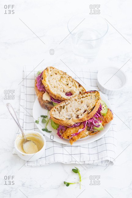 Lunch sandwich with avocado, fried chicken and sliced red cabbage served with mustard sauce