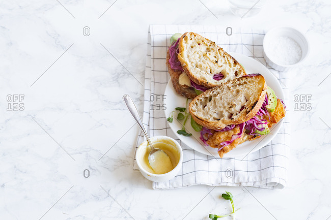 Lunch sandwich with avocado, fried chicken and sliced red cabbage served with mustard sauce