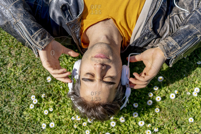 Man lying on flower meadow with headphones