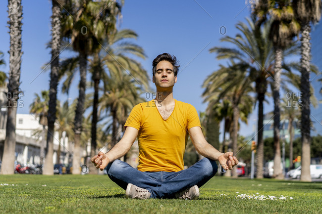 Spain- Barcelona- man practicing yoga on lawn in the city