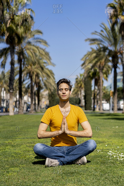 Spain- Barcelona- man practicing yoga on lawn in the city